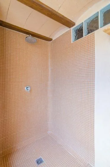 A tiled shower area with a wall-mounted showerhead and floor drain.