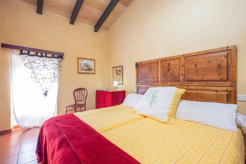 A bedroom with a yellow bedspread and a large wooden headboard.