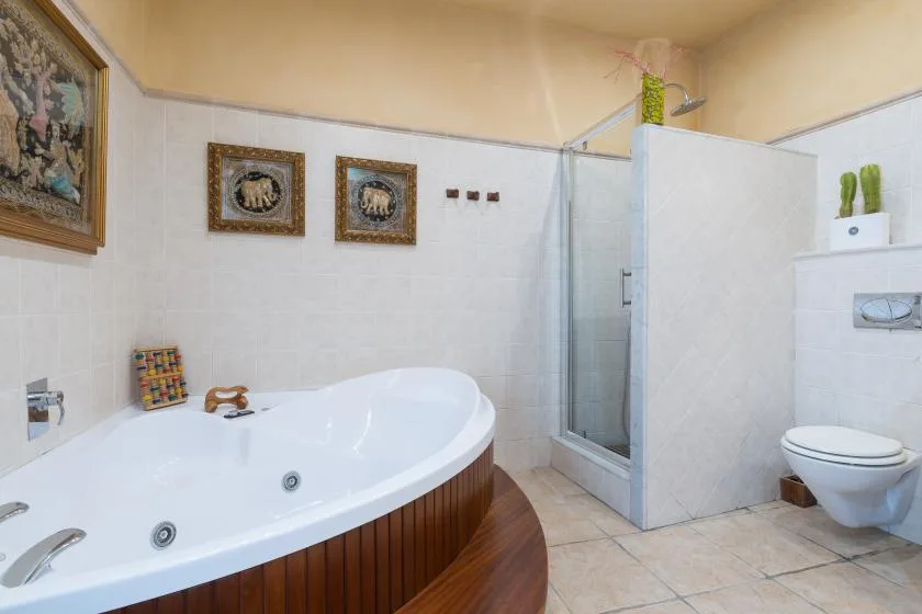 A tiled bathroom with a large bathtub and a glass-enclosed shower.