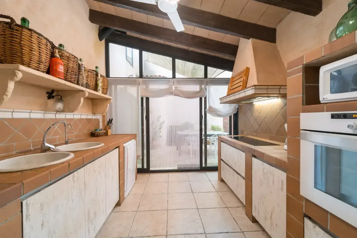A tiled kitchen with counters on both sides and a glass door at the far end.