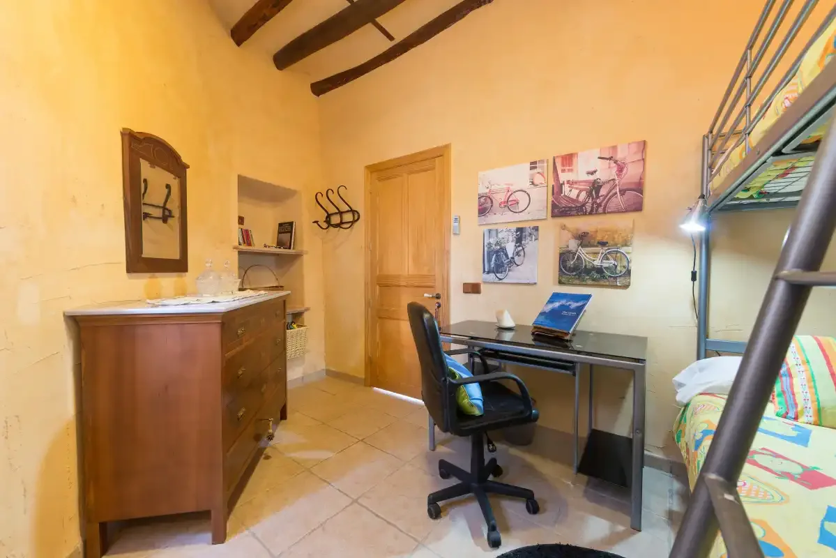 A bedroom workspace with a desk and chair beside bunk beds.