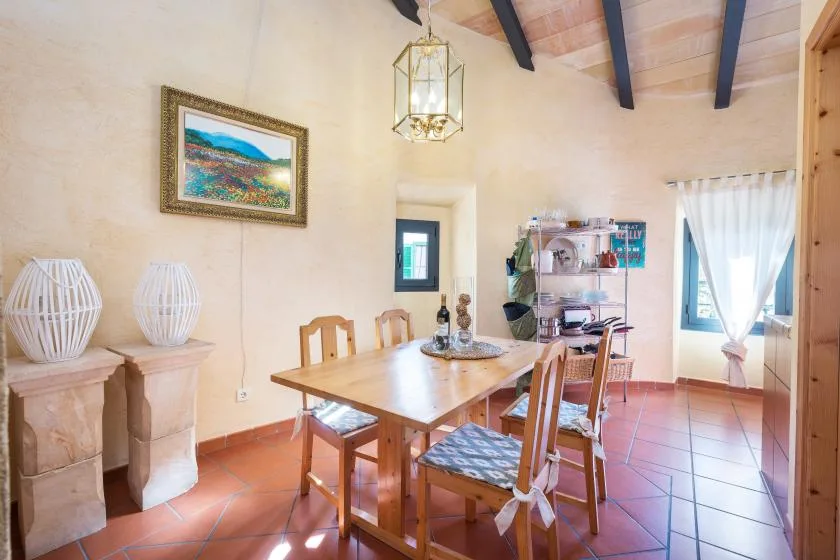 A dining room with a wooden table and chairs beneath exposed ceiling beams.