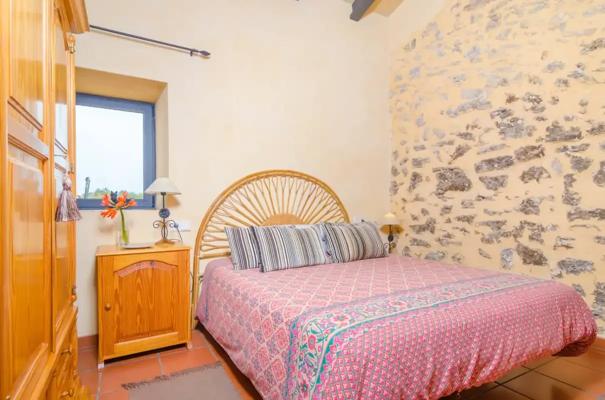A bedroom with a bed beside a stone accent wall.