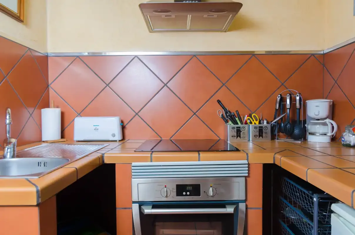 A kitchen with a built-in oven, tiled backsplash, and countertop appliances.