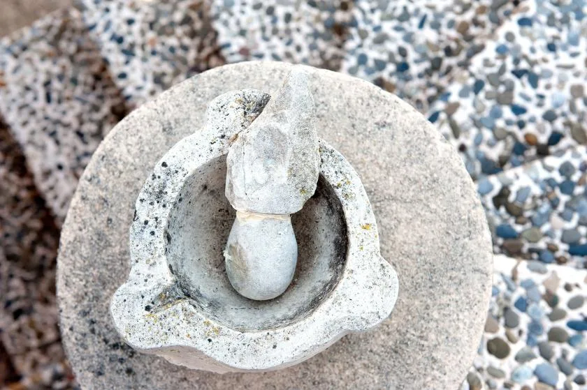 A stone fountain sits on a pebble-patterned surface.