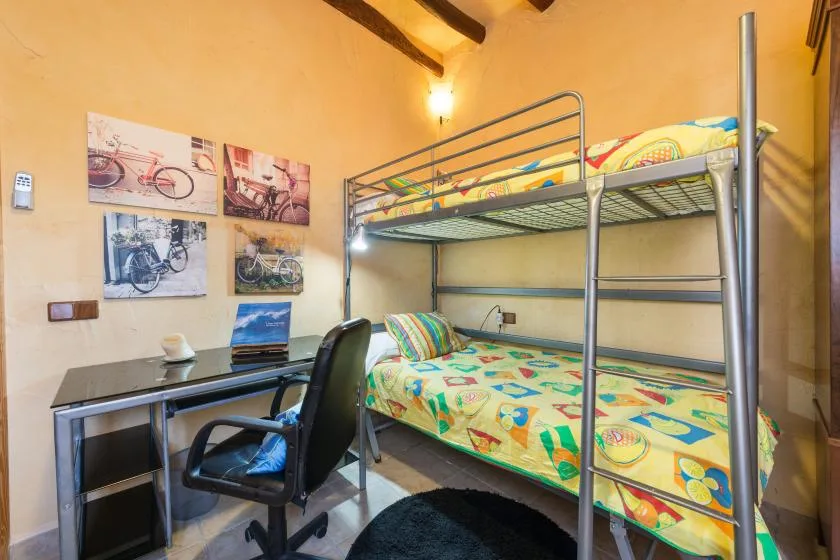A bedroom with a metal bunk bed and a desk beside it.