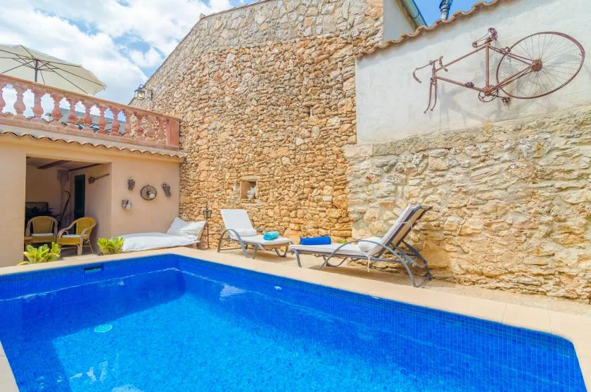 A swimming pool sits beside a stone courtyard with lounge seating.