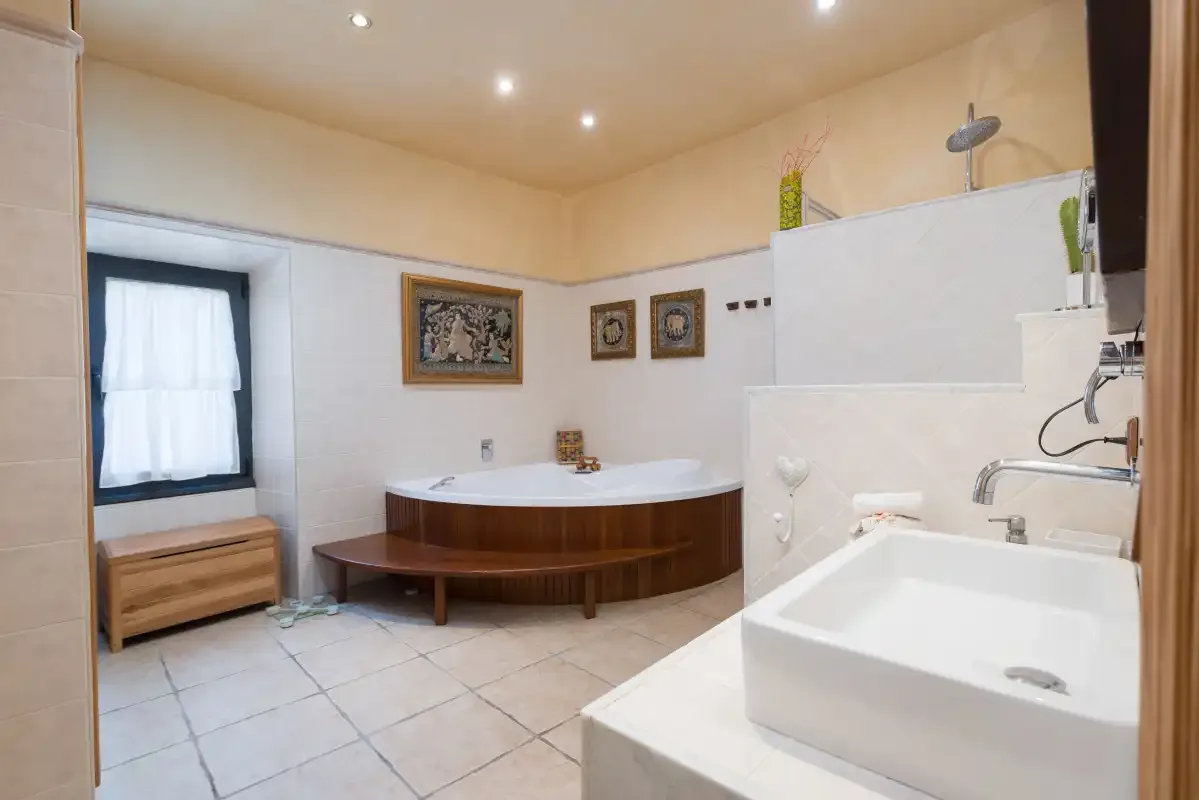 A bathroom with a corner bathtub and a separate sink.