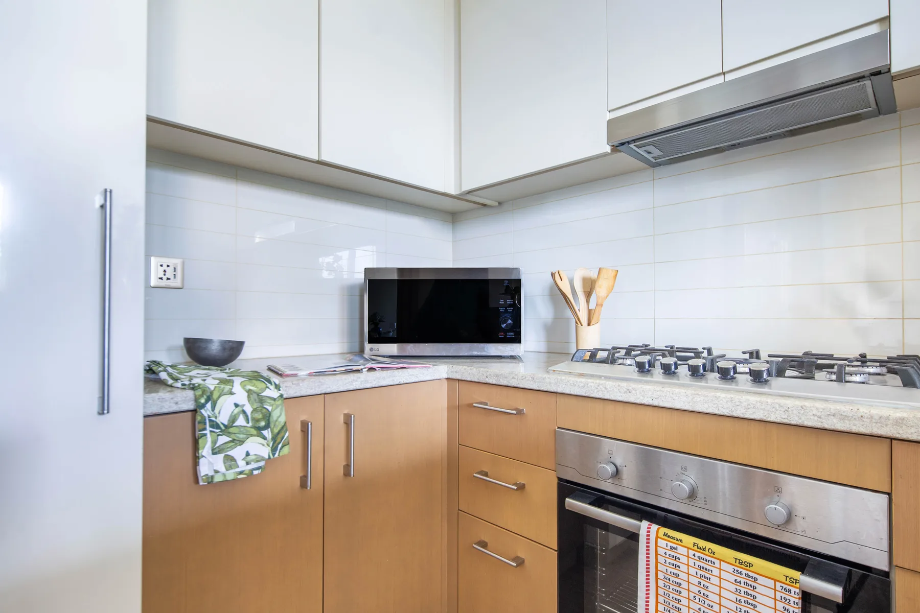 A bright kitchen with wooden cabinets, a microwave, and a cooktop.