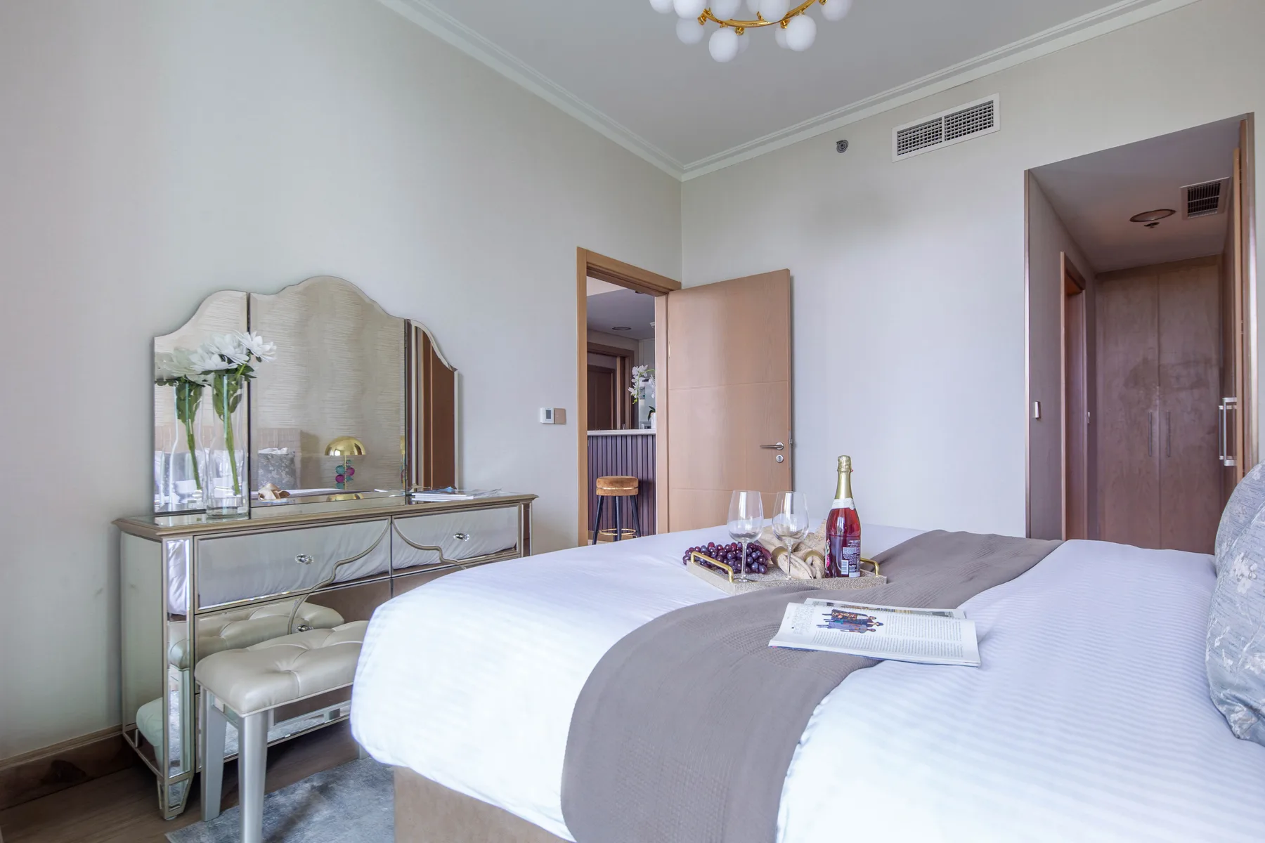 A bedroom with a bed, mirrored dresser, and an open doorway.