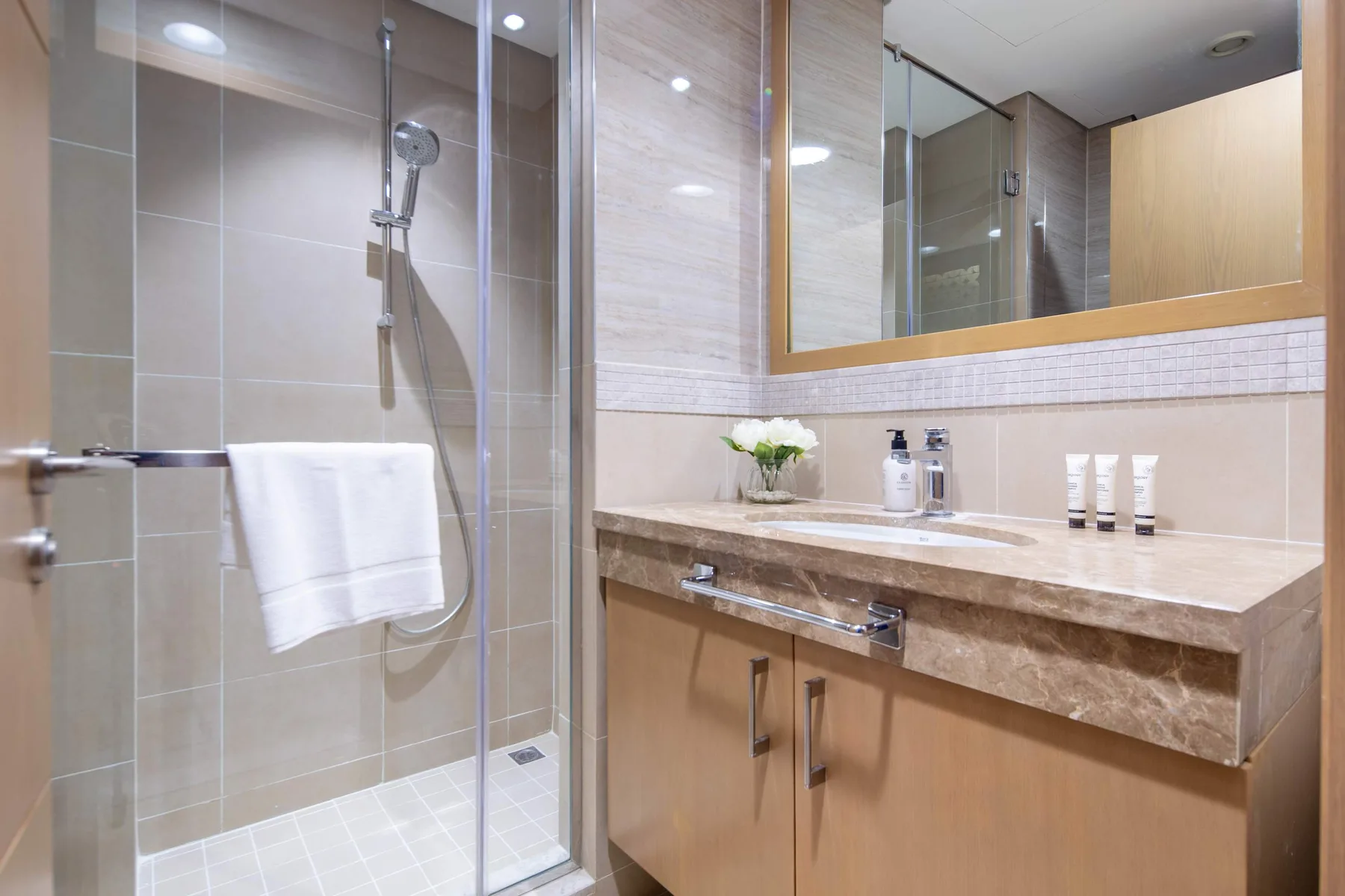 A bathroom with a glass shower and a sink vanity.