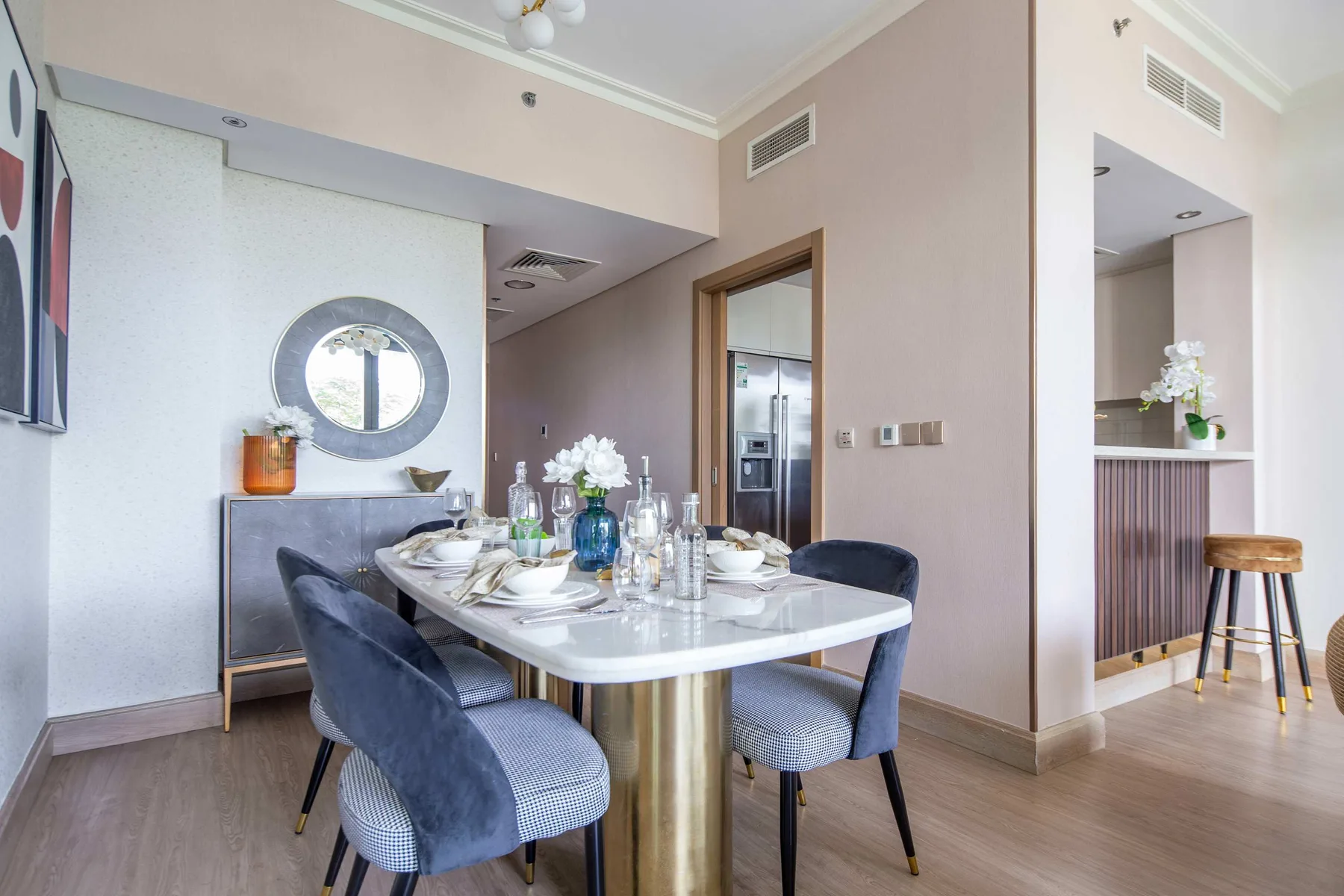 Comedor con una mesa puesta y asientos tapizados junto a una pared con espejo.