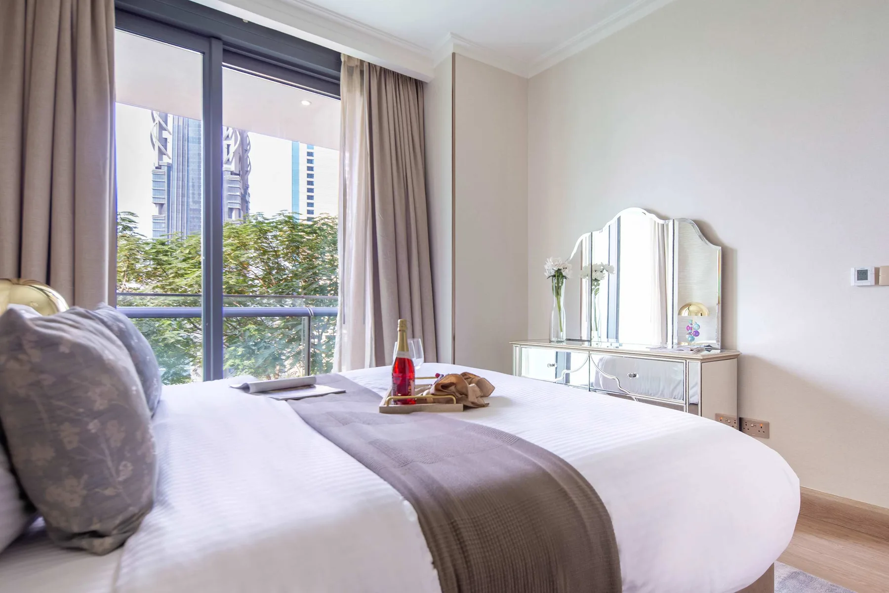 A bright bedroom with a neatly made bed beside a large window.