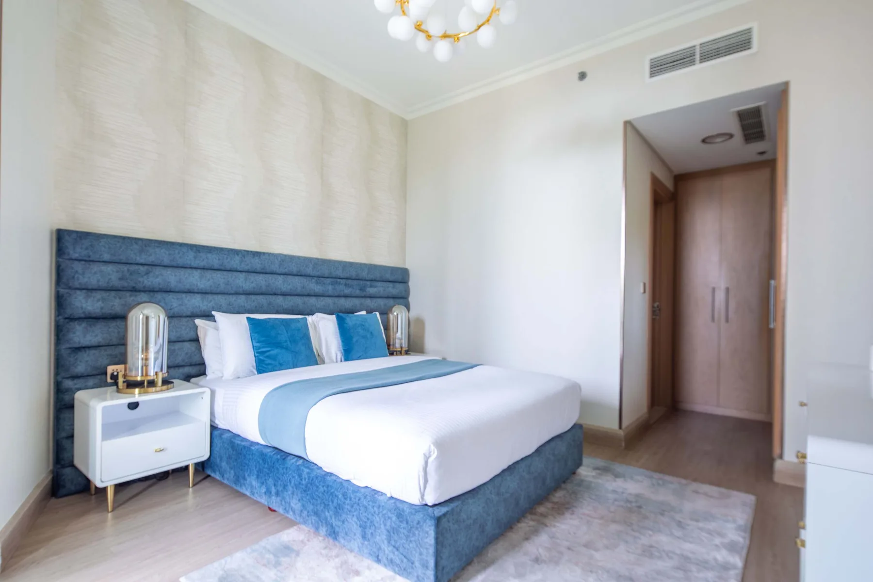 A bedroom with a blue upholstered bed and white bedding.