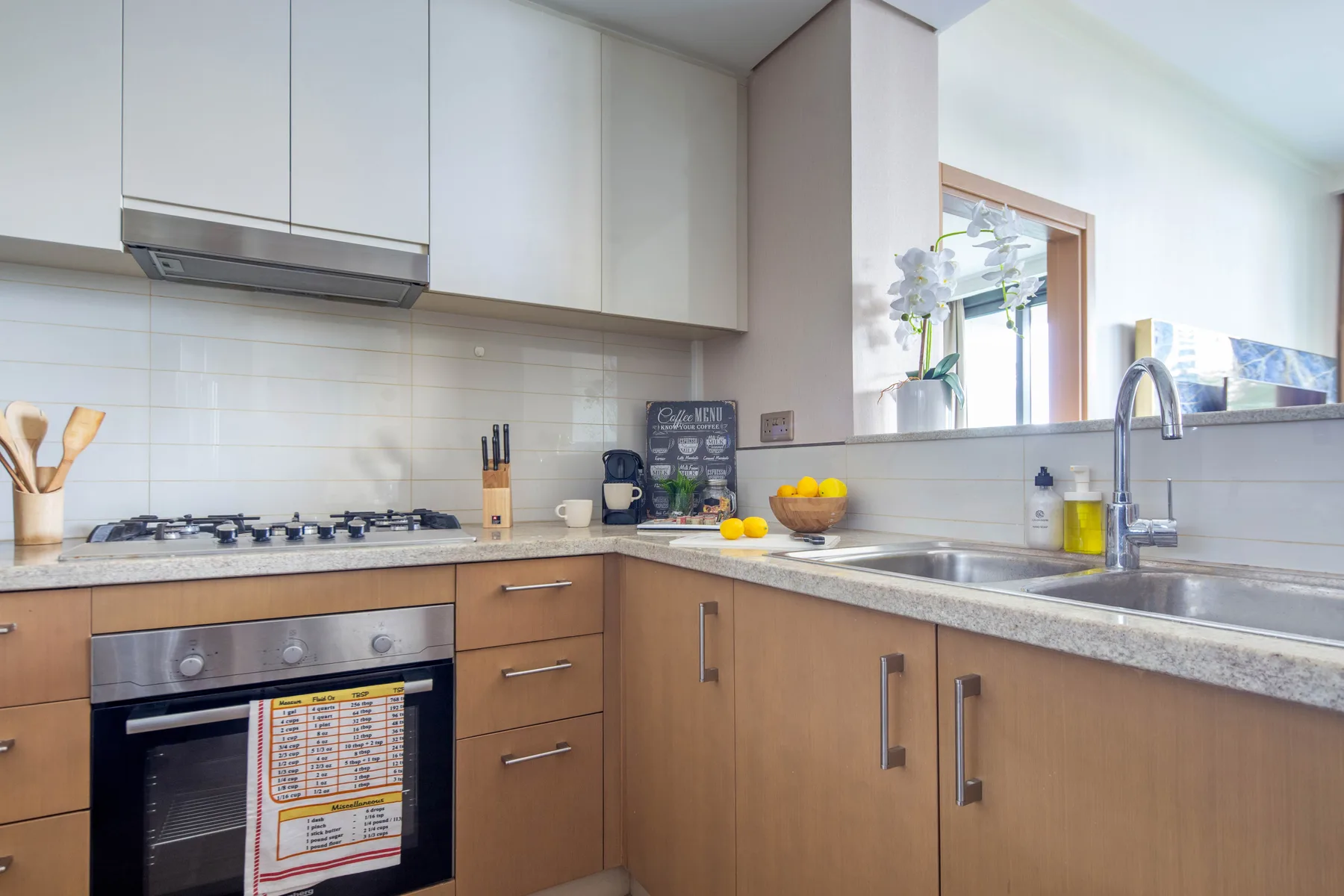 A bright kitchen with wooden cabinets, a cooktop, and a sink.