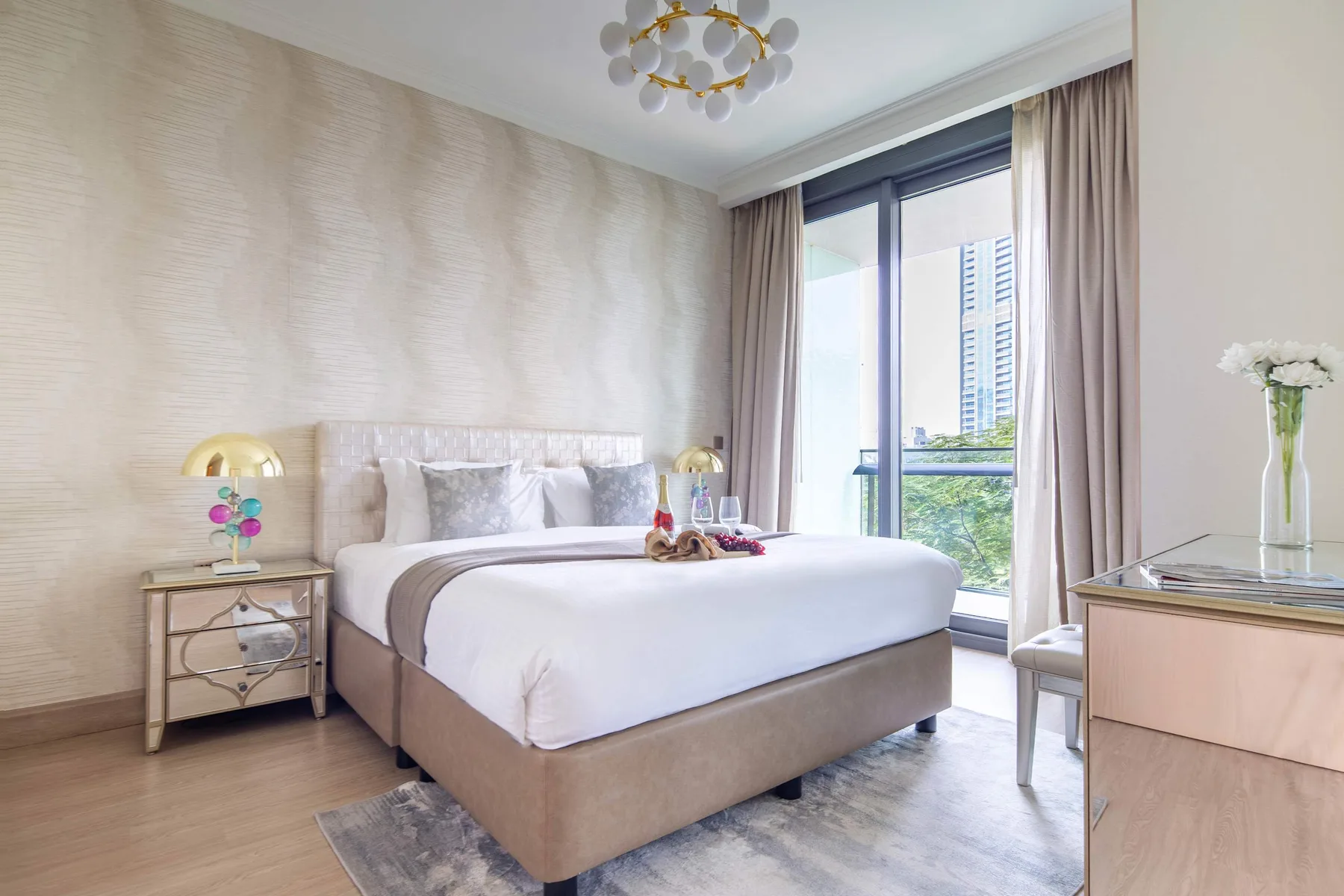 A bright bedroom with a neatly made bed beside a large window.