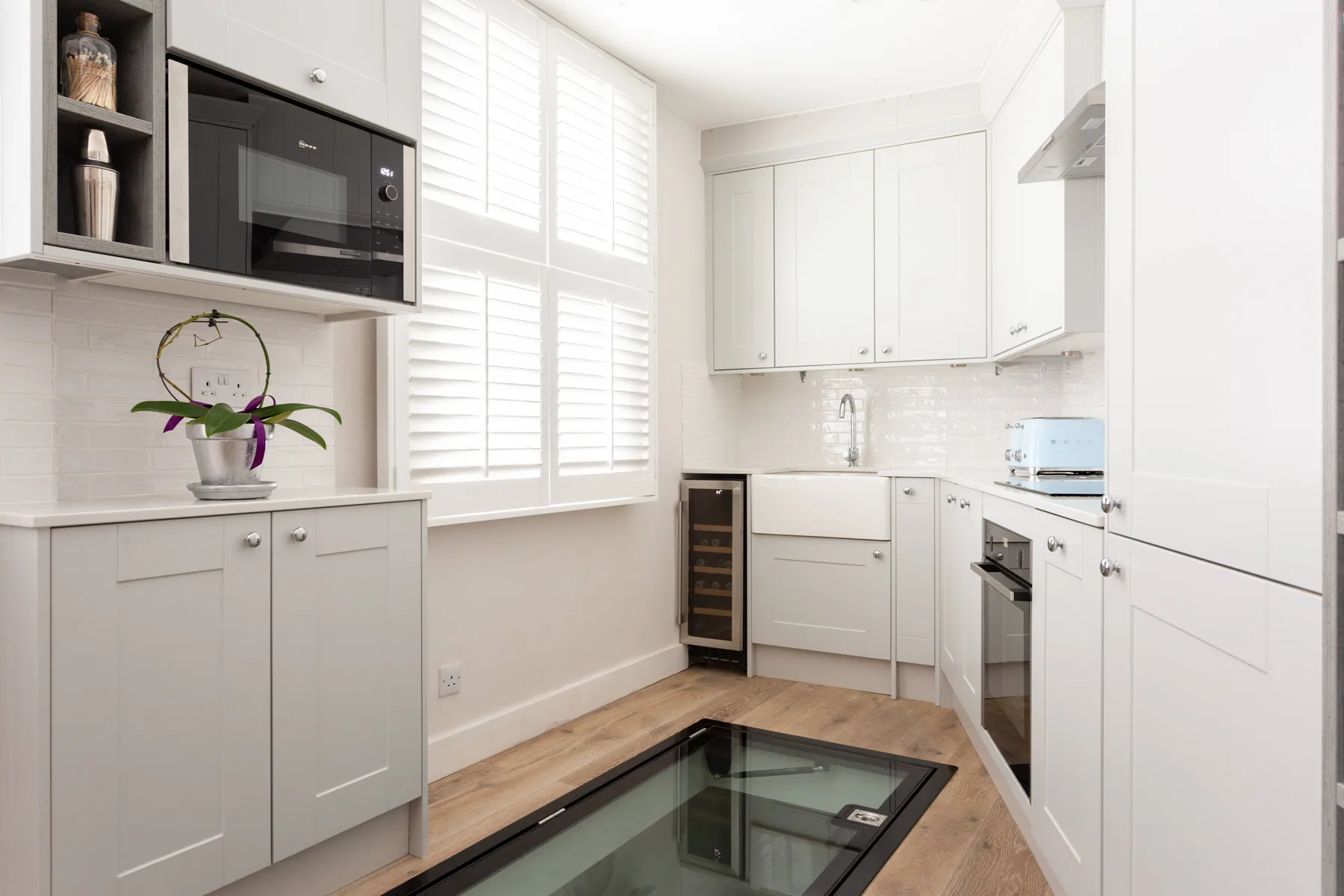 A bright white kitchen with built-in cabinetry and a glass cooktop.