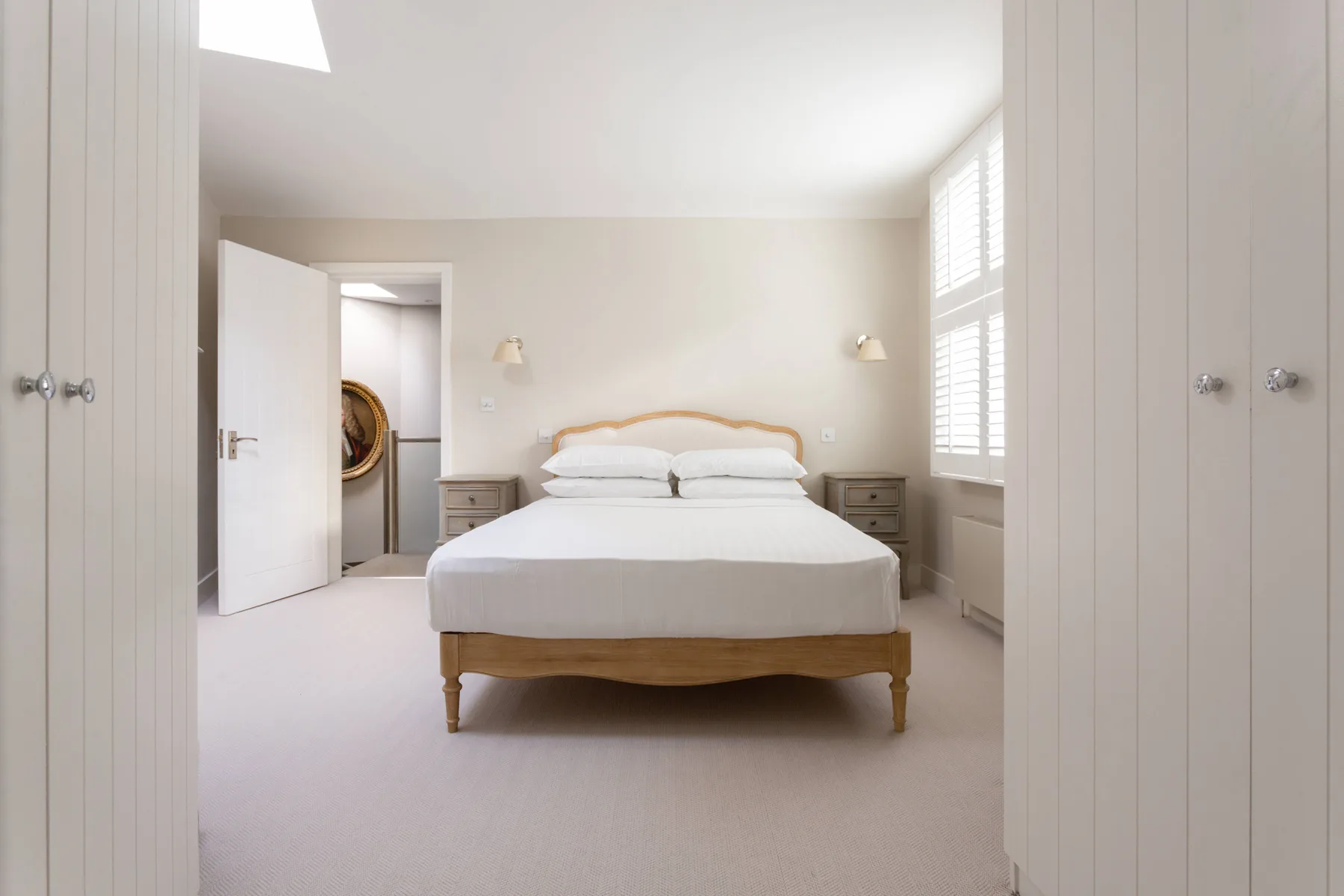 A bright bedroom with a neatly made bed and windows along one wall.