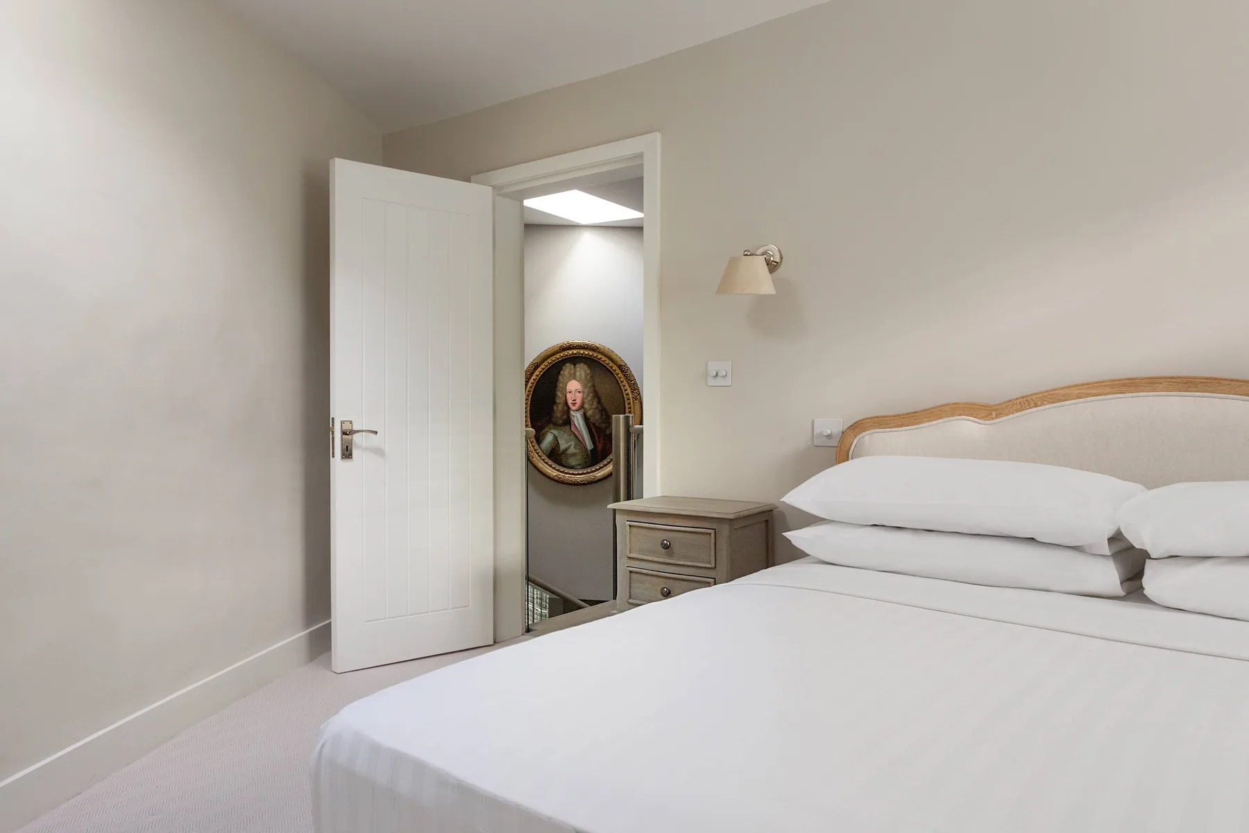 A bedroom with a neatly made bed and an open doorway.