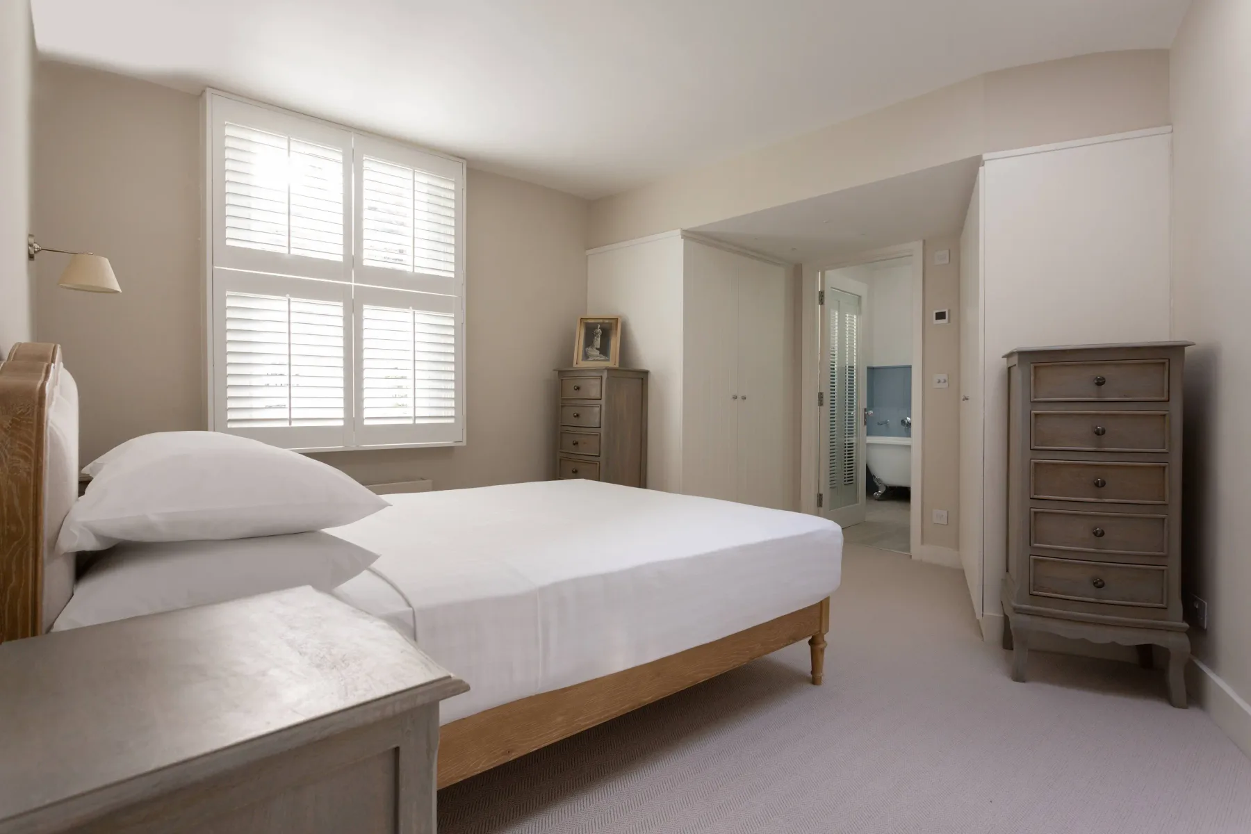 A bedroom with a bed beneath a large window and an open doorway.