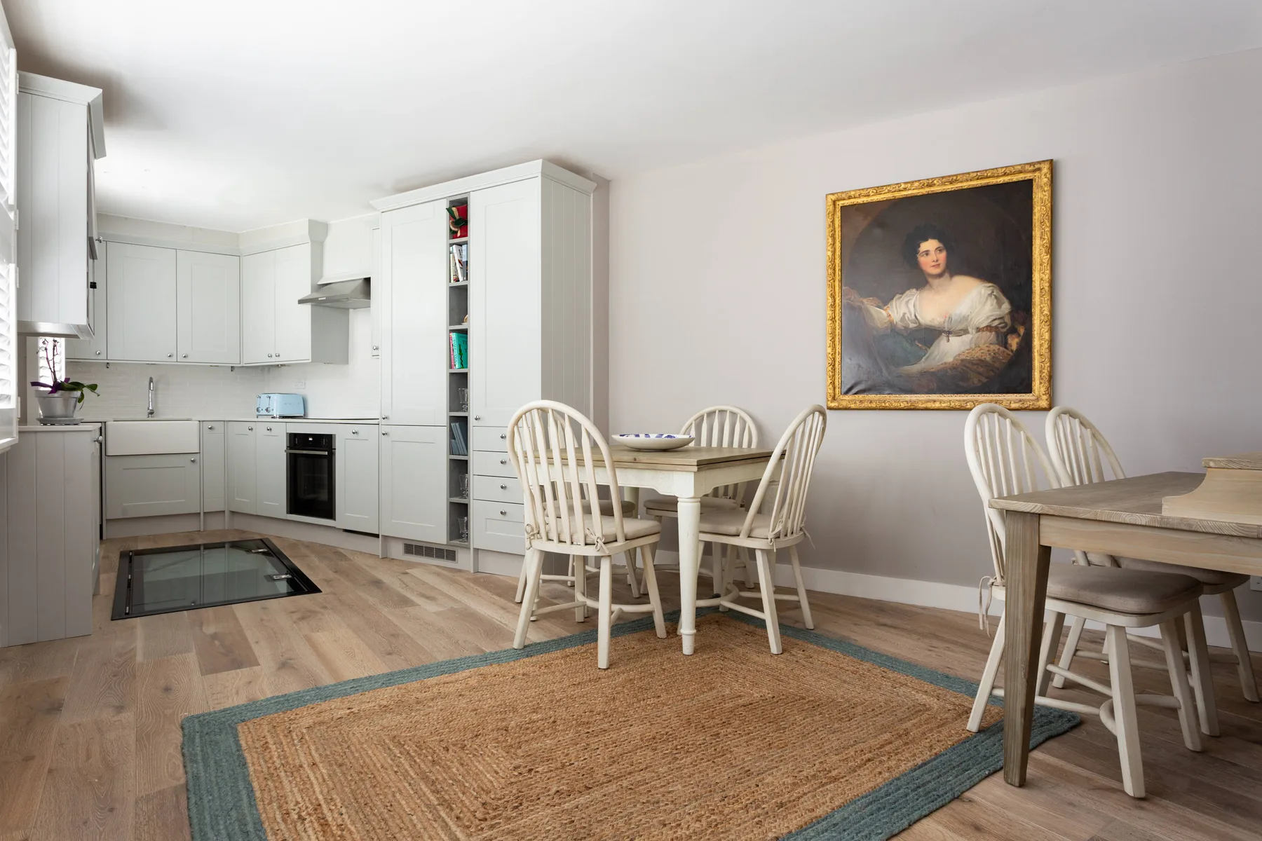 A bright kitchen and dining area with white cabinetry and a wooden table.