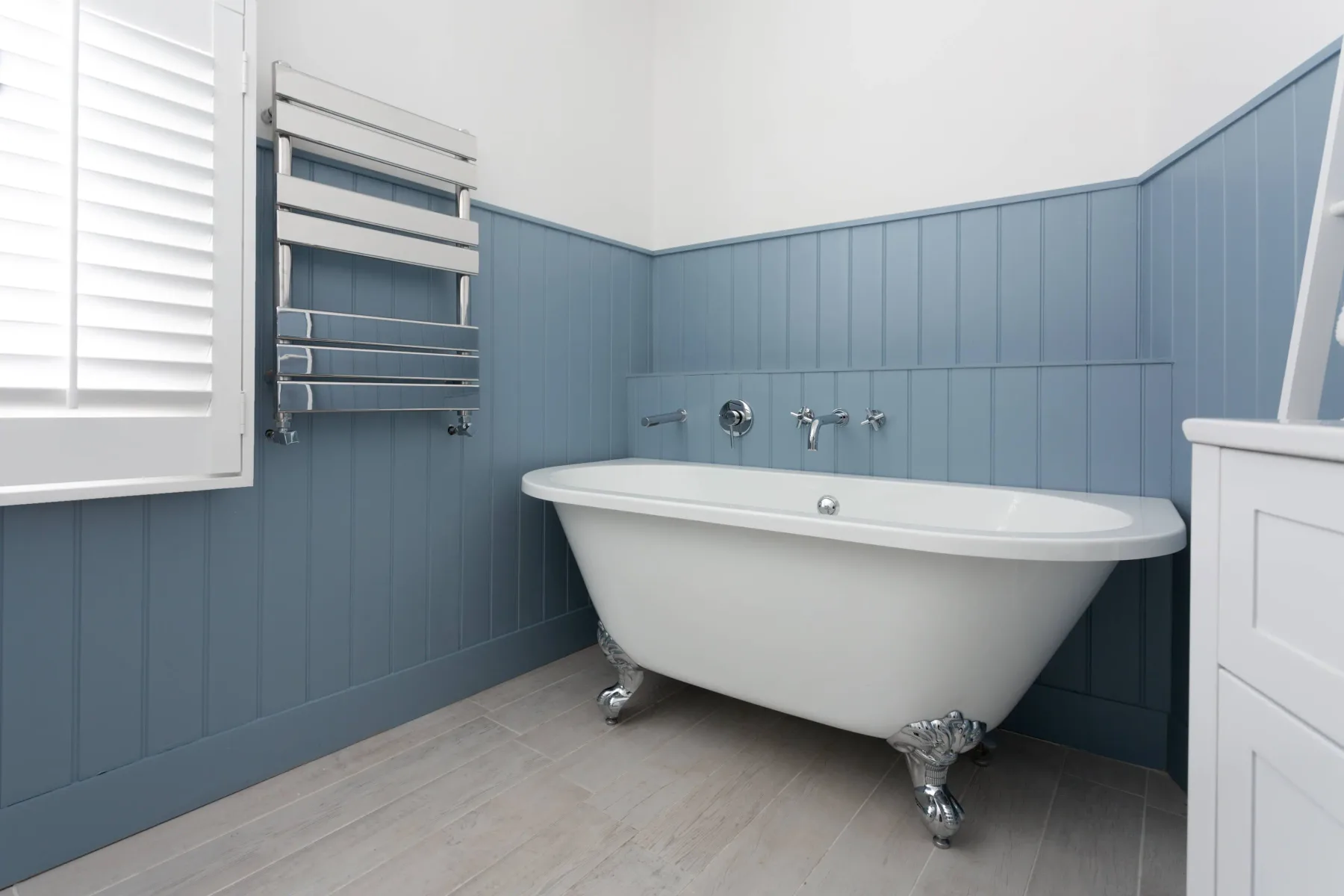 A bathroom with a freestanding bathtub and blue paneled walls.