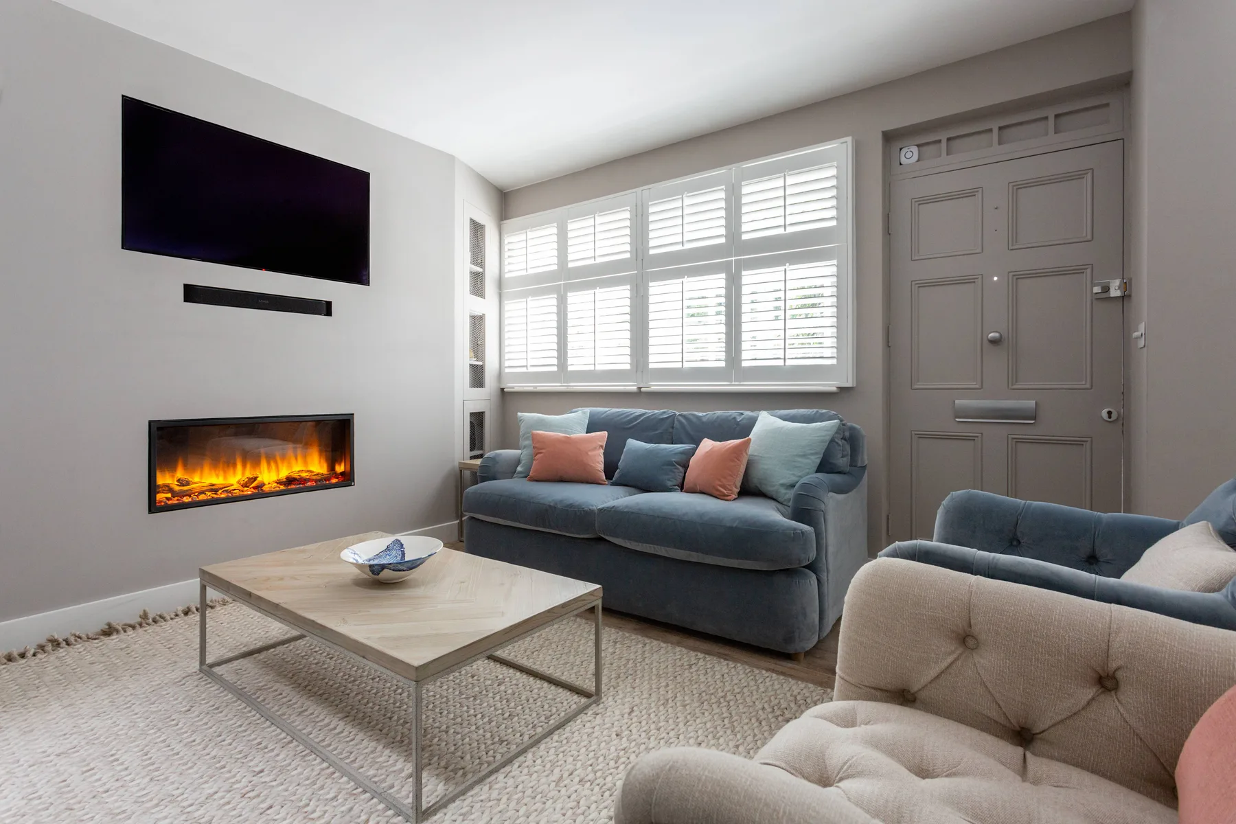 A living room with seating, a coffee table, and a wall-mounted television.