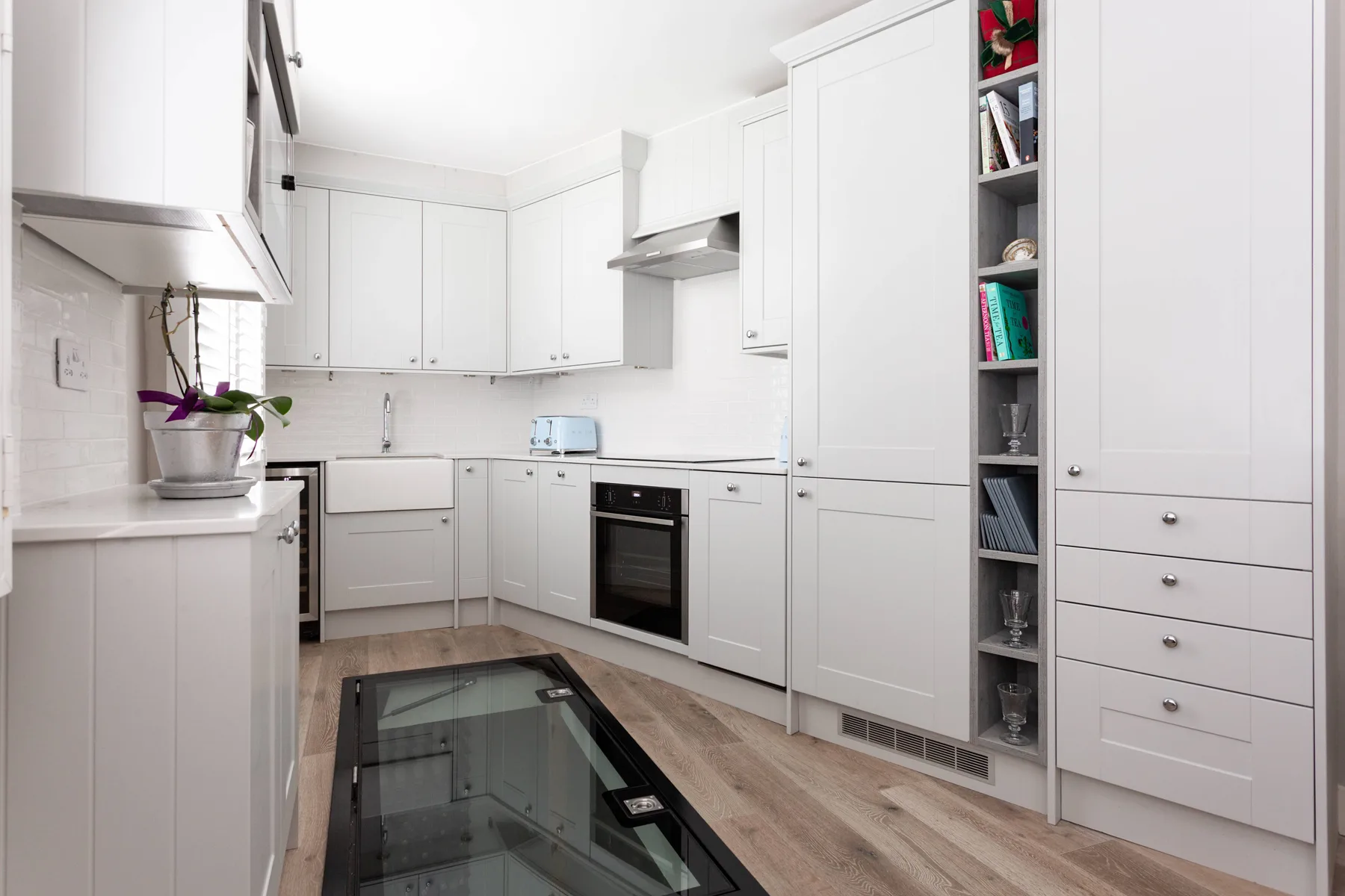 A bright kitchen with white cabinetry and a glass cooktop.
