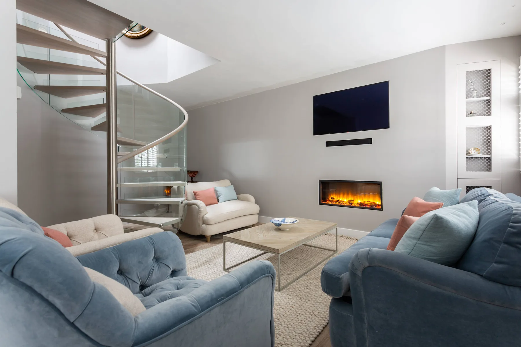 Living room with blue seating, a wall-mounted television, and a lit fireplace.