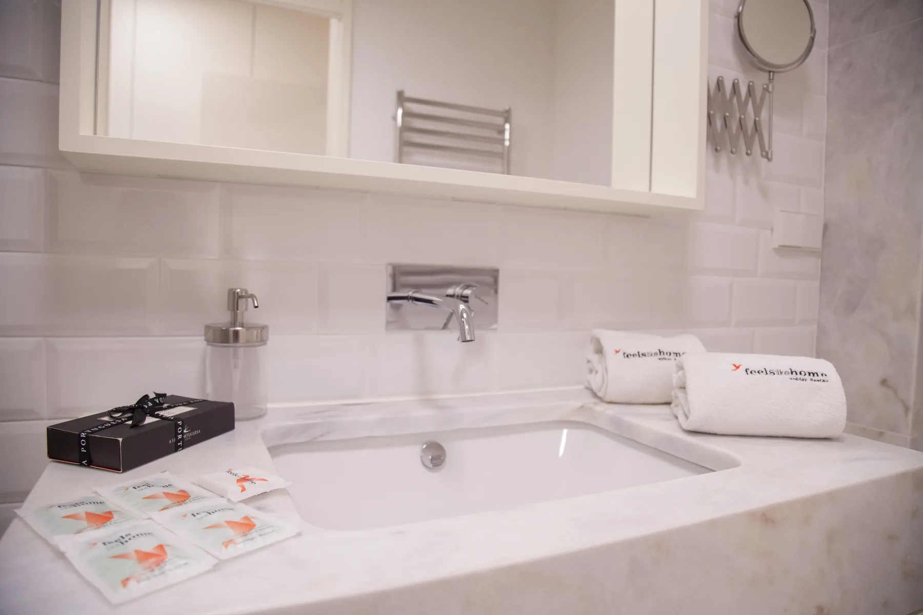 Un tocador de baño con lavabo, espejo de pared y toallas dobladas.
