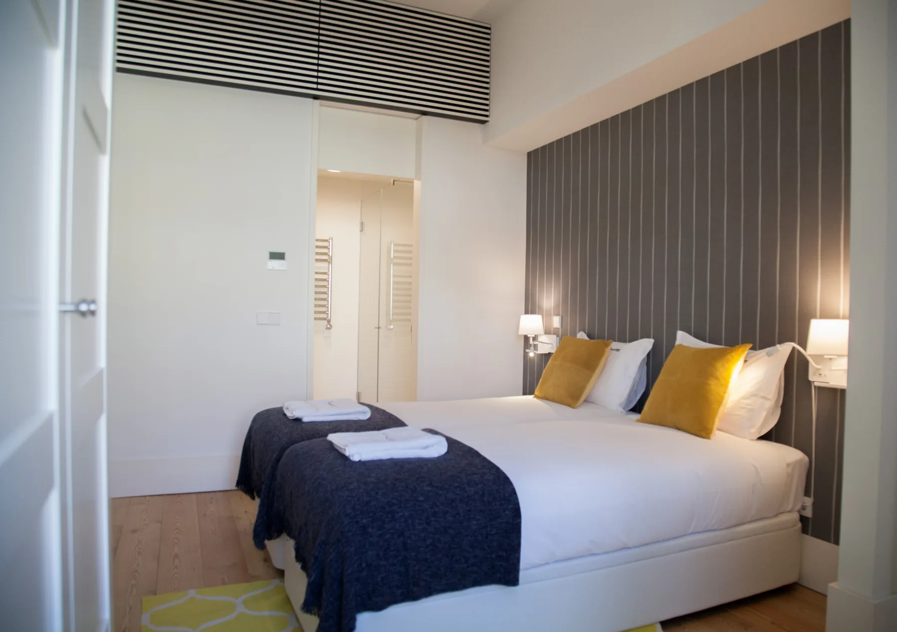Un dormitorio con una cama bien tendida y una pared oscura.