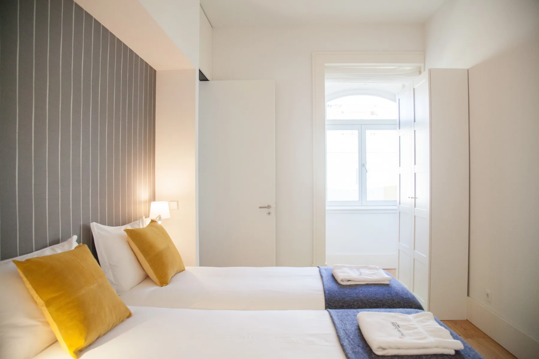 Un dormitorio luminoso con camas y toallas dobladas.
