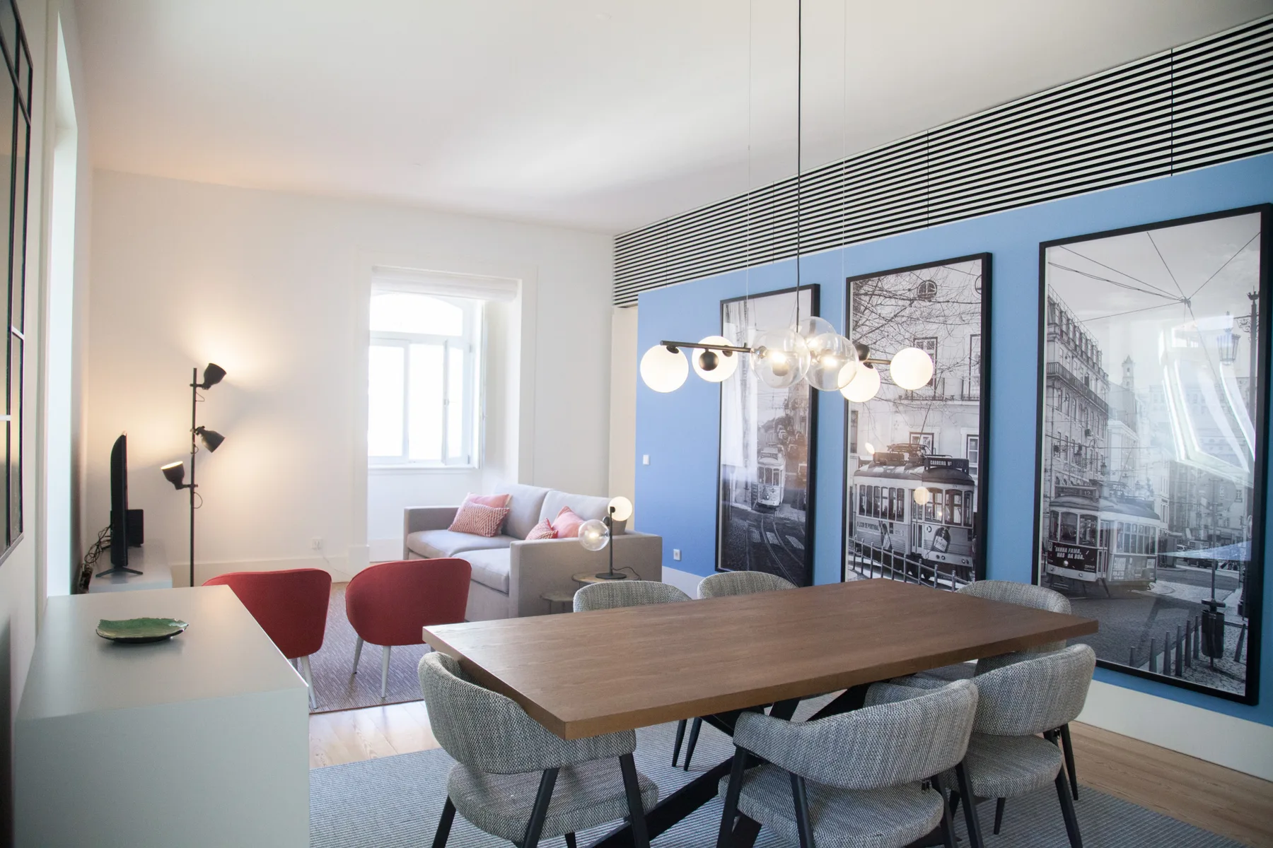 Comedor con una mesa de madera y asientos junto a una pared azul.