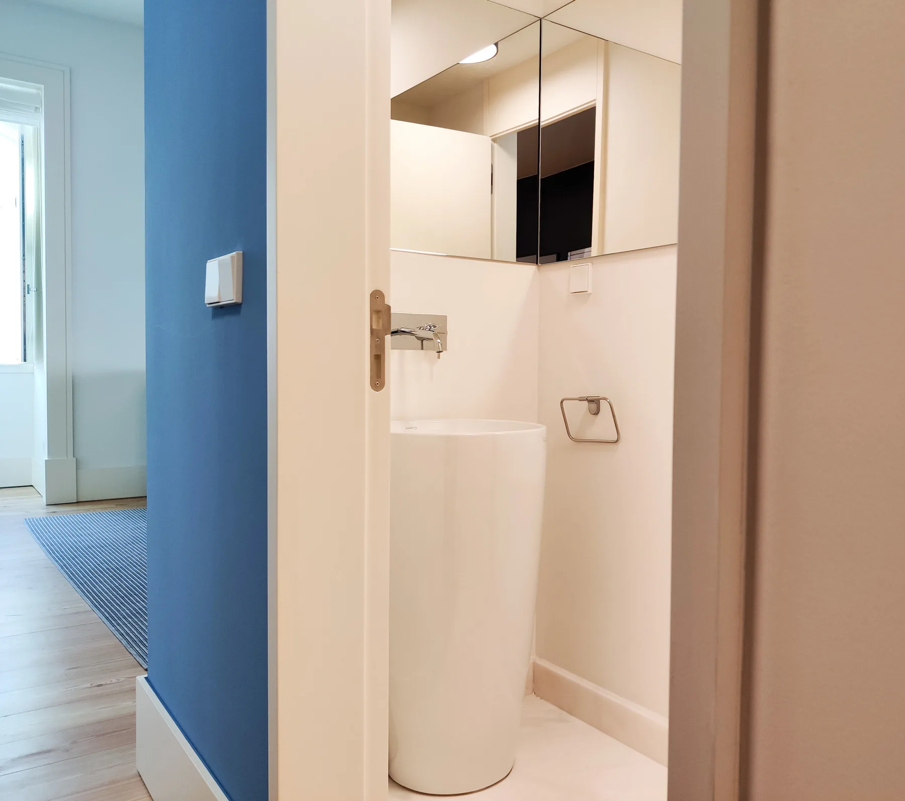 Un baño con un lavabo blanco y armarios con espejo.