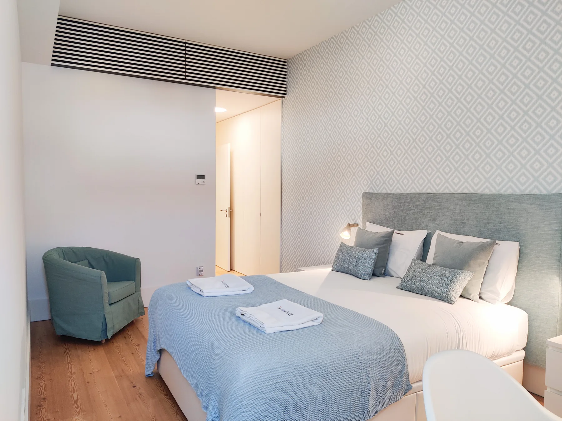 Un dormitorio con una cama vestida con ropa de cama blanca y azul.