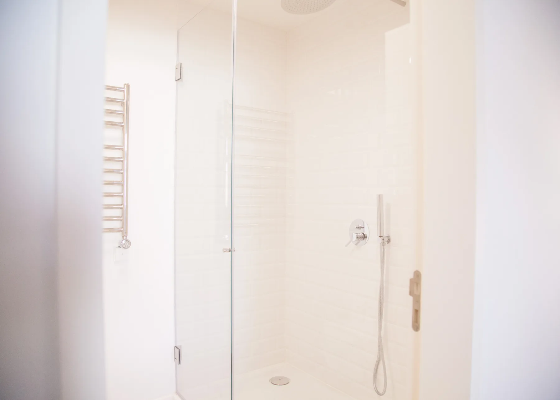 Un baño luminoso con una ducha de cristal y accesorios en la pared.
