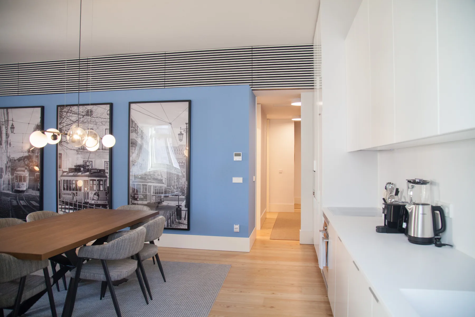 Comedor con una mesa de madera, asientos grises y una pared azul.