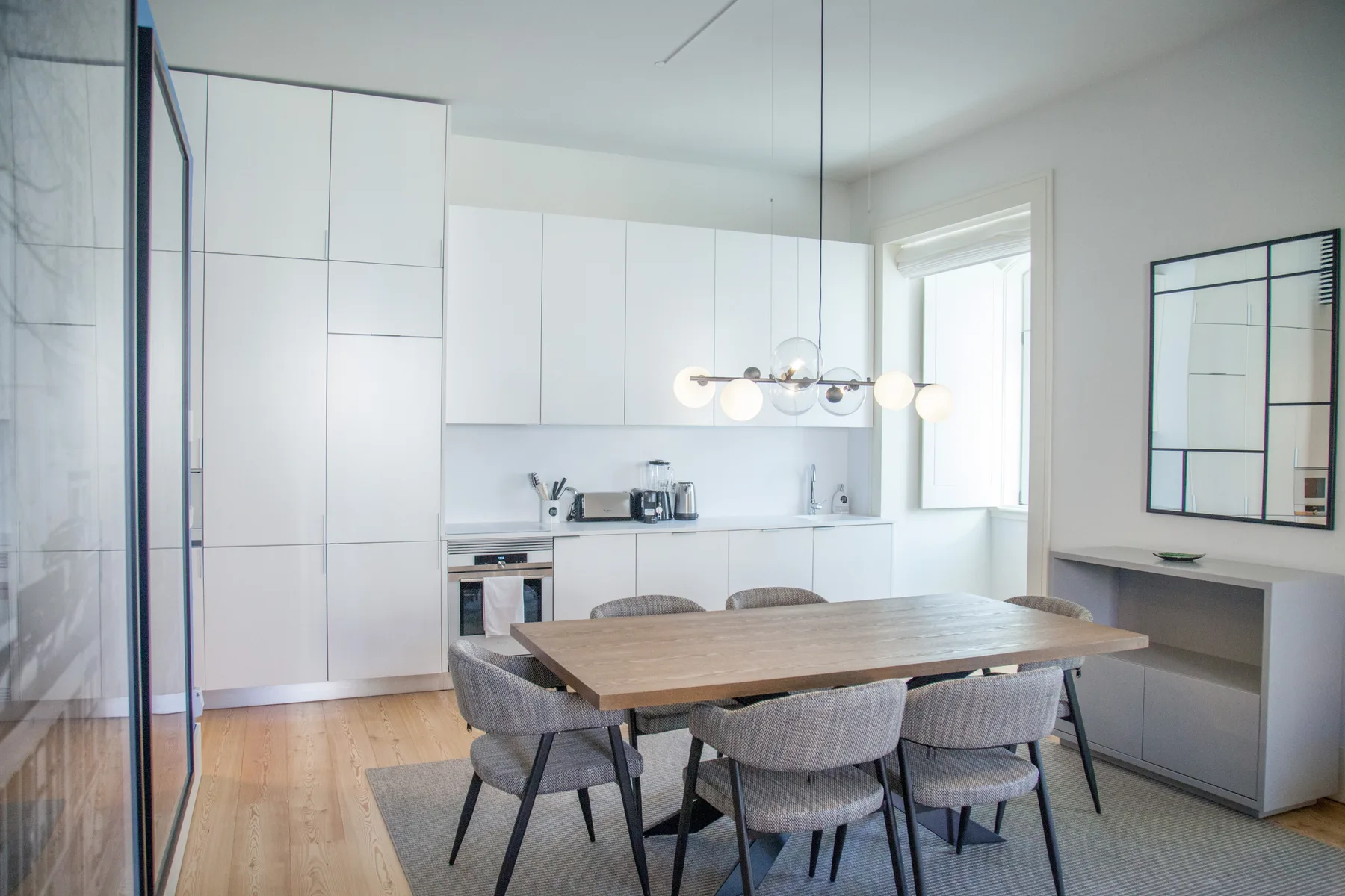 Un comedor luminoso con una mesa de madera junto a una cocina compacta.