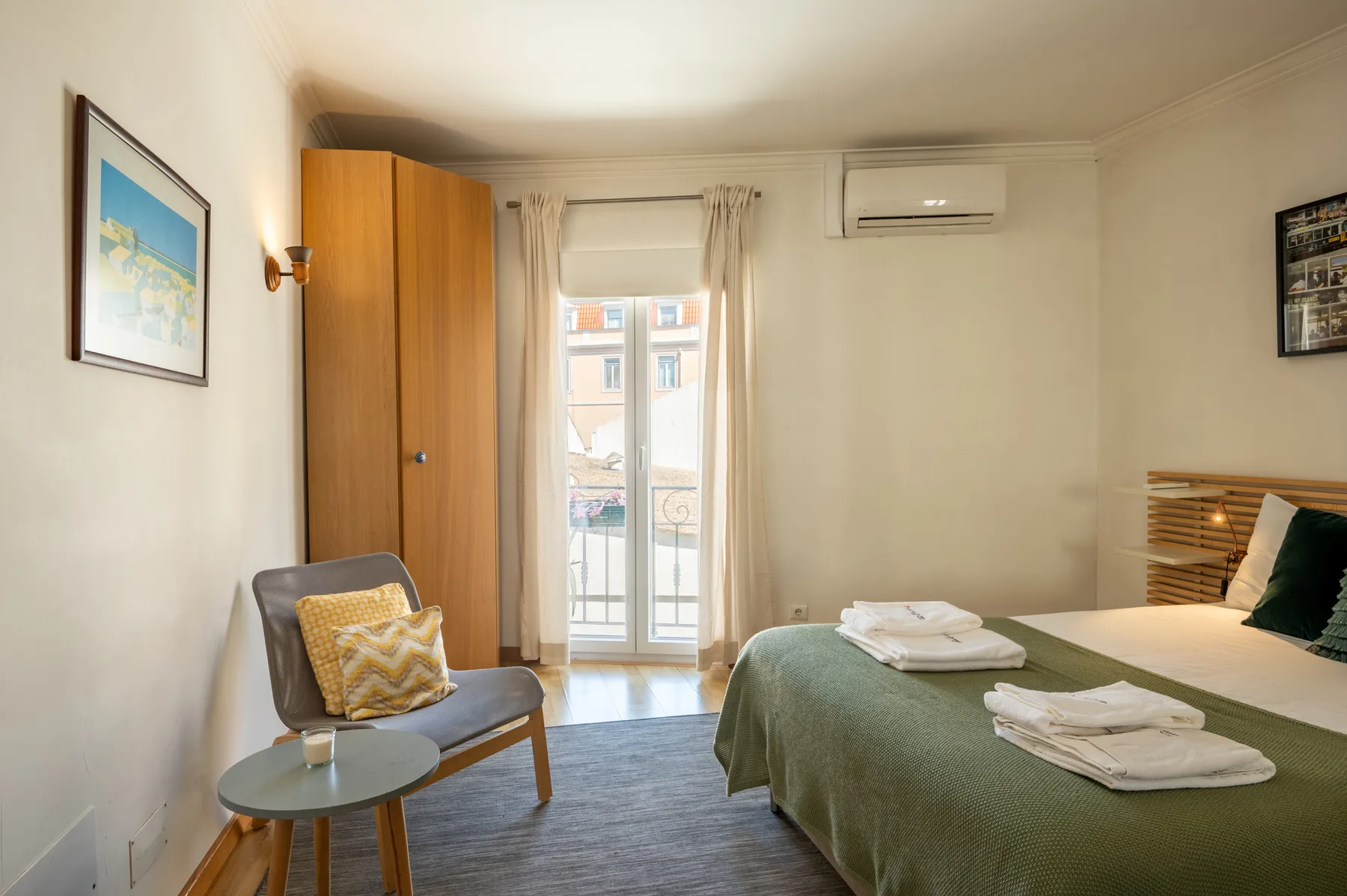 Un dormitorio con una cama cubierta con ropa de cama verde y una pequeña zona de estar.