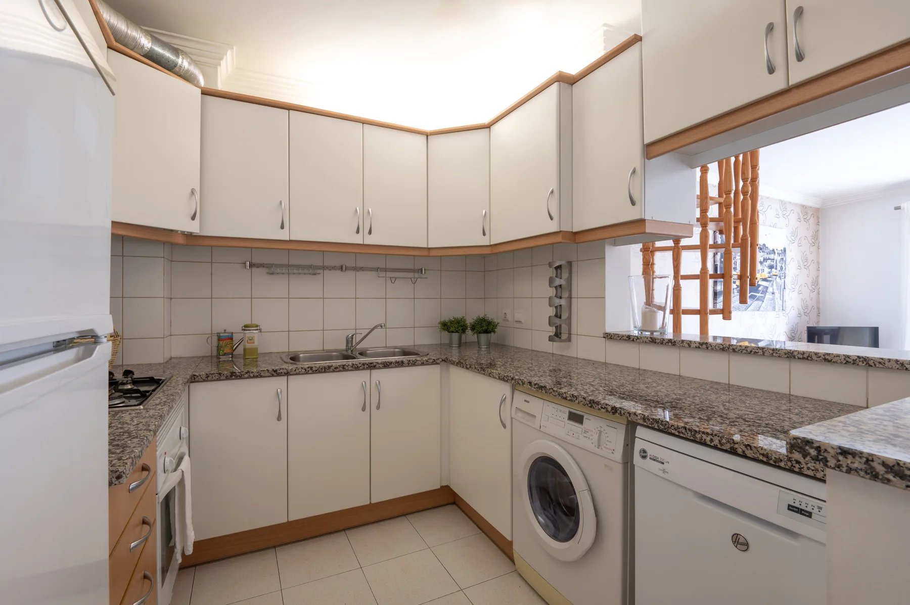 Una cocina compacta con gabinetes claros, salpicadero de azulejos y encimera.