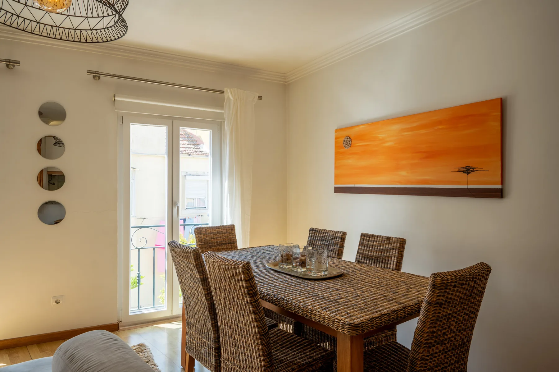 Comedor con una mesa y sillas de tejido junto a una puerta acristalada luminosa.