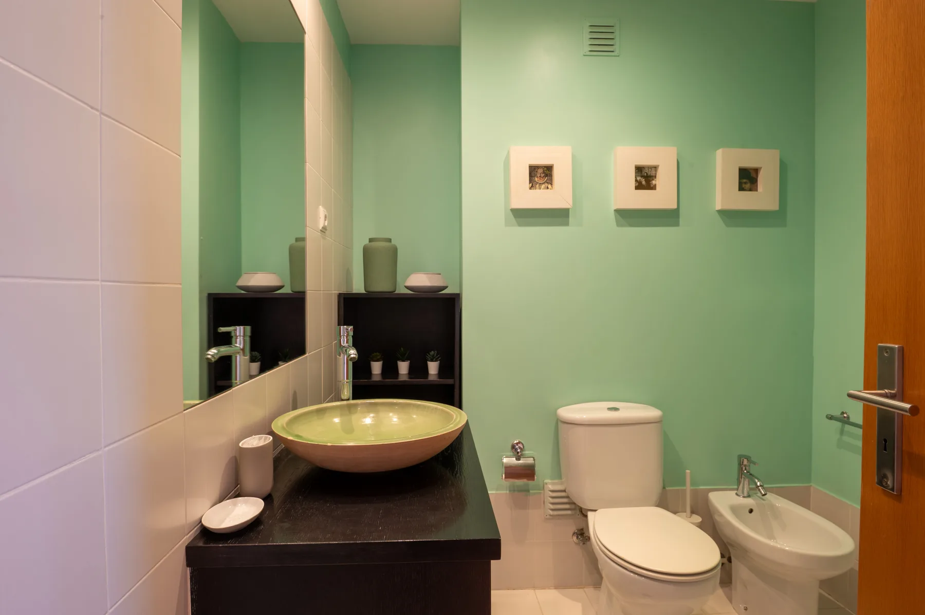 Un baño con lavabo, inodoro y paredes verdes.