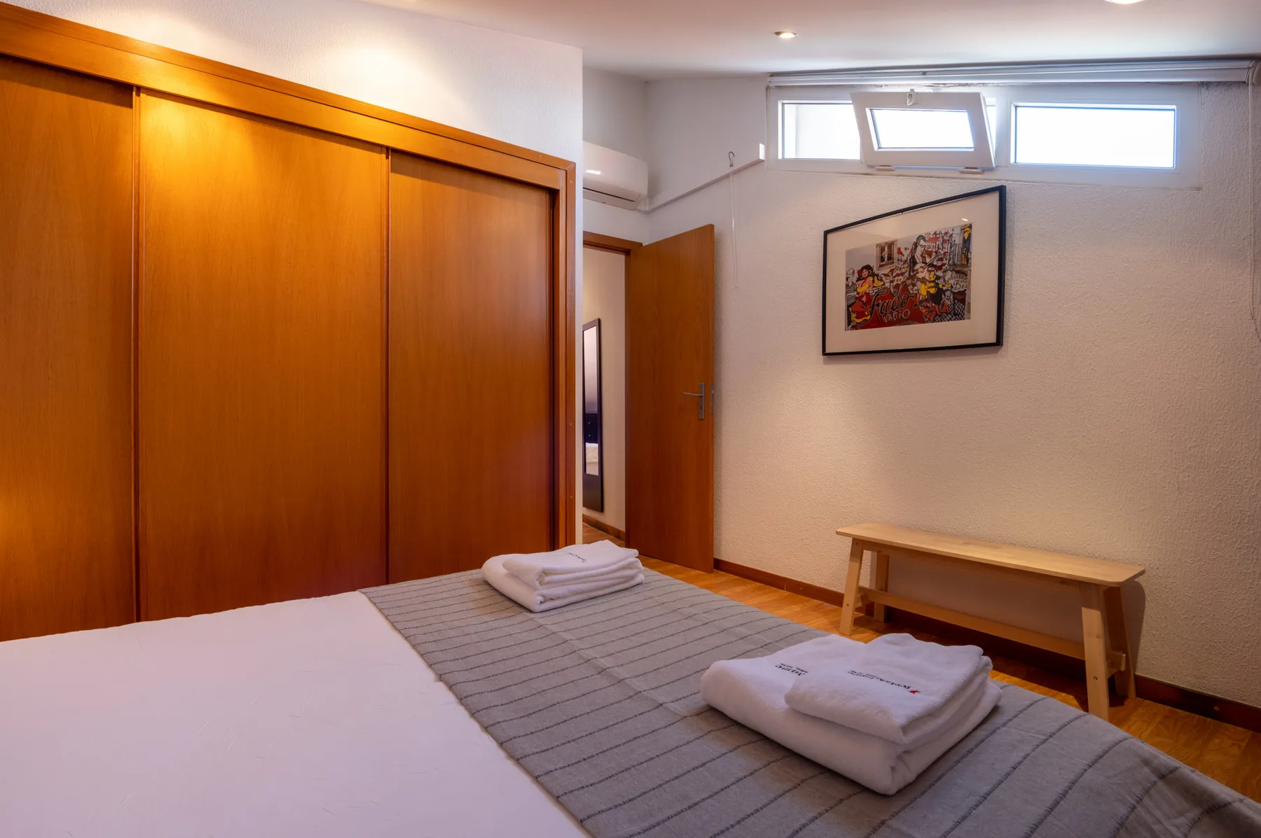 Un dormitorio con una cama, toallas dobladas y un banco de madera.