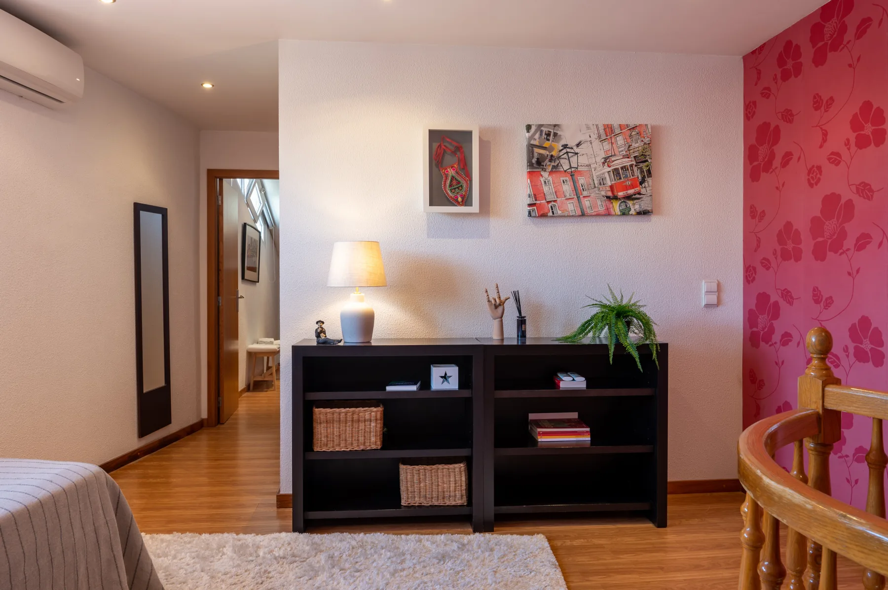 Un dormitorio con una estantería oscura, cuadros enmarcados y una cama de madera.