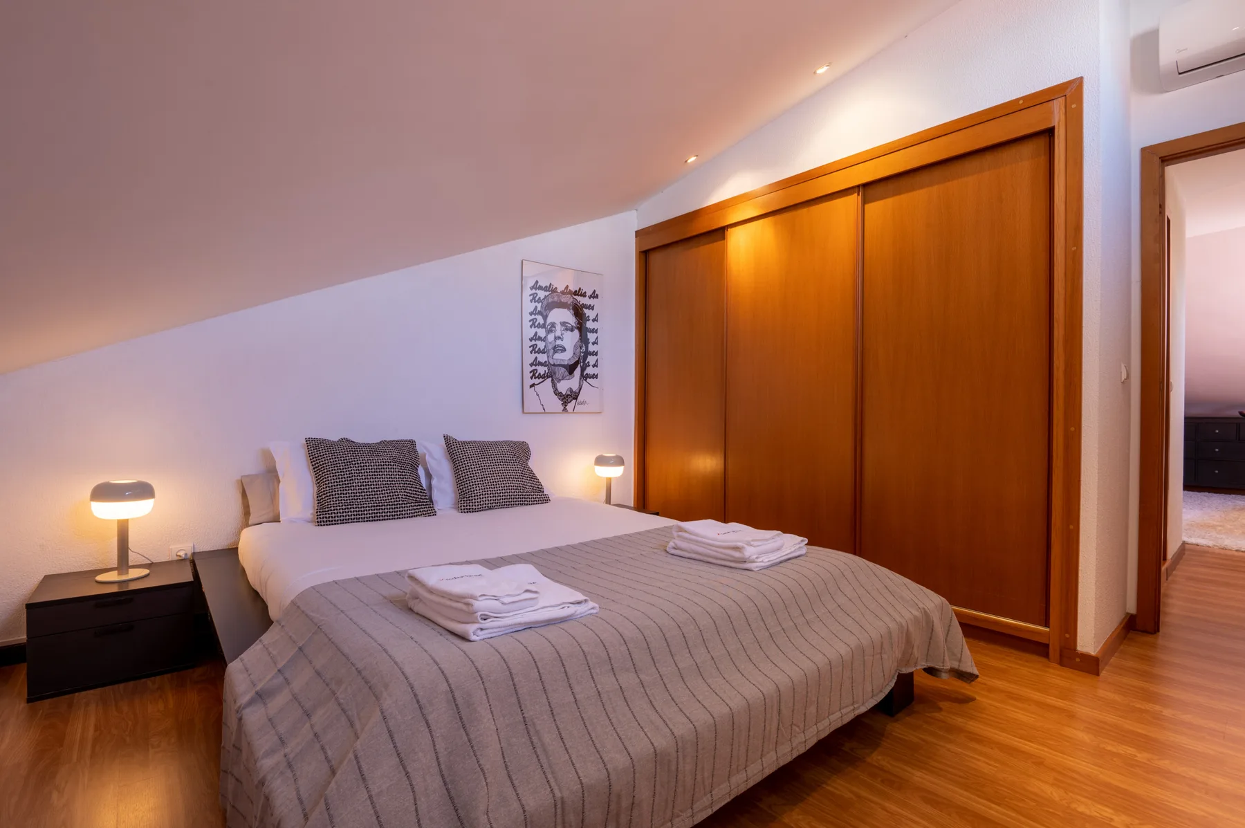 Dormitorio con una cama bien hecha y un armario de madera.