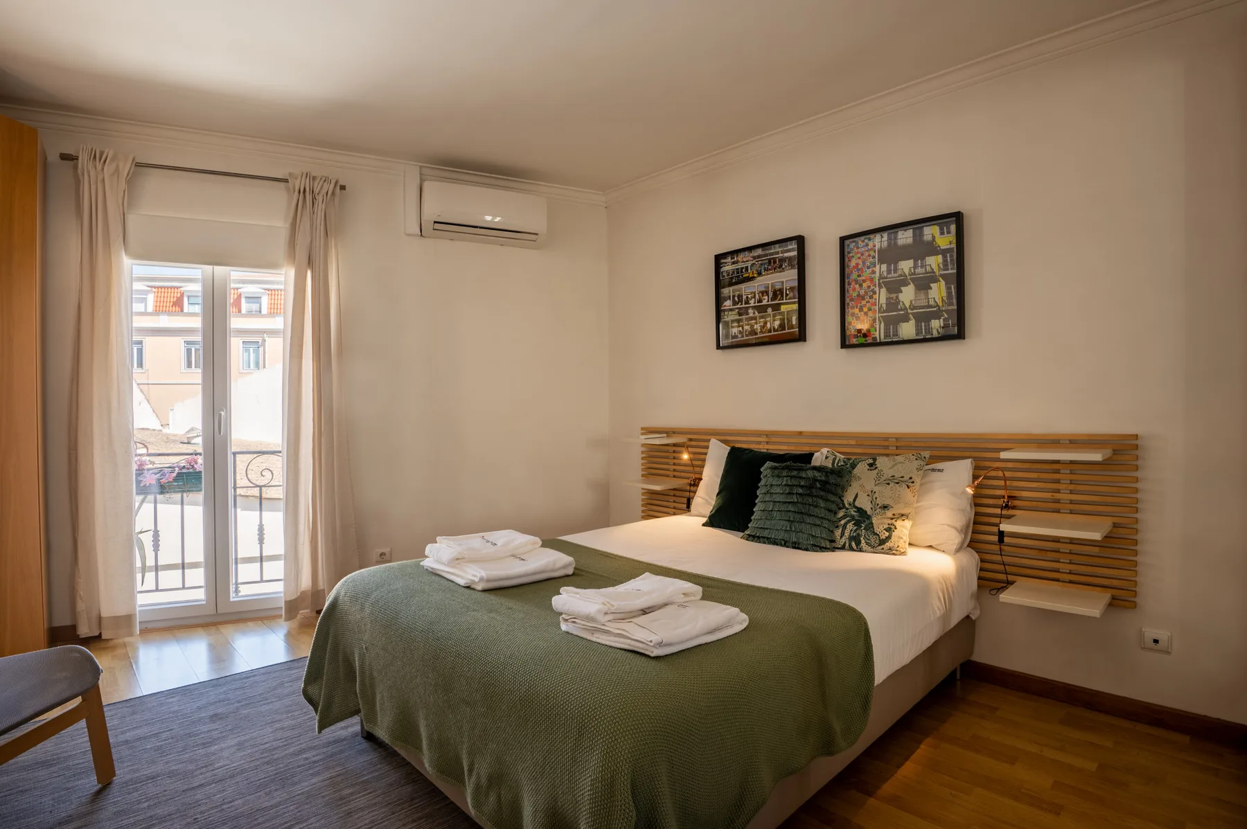 Un dormitorio con una cama doble, toallas dobladas y una ventana con cortinas.