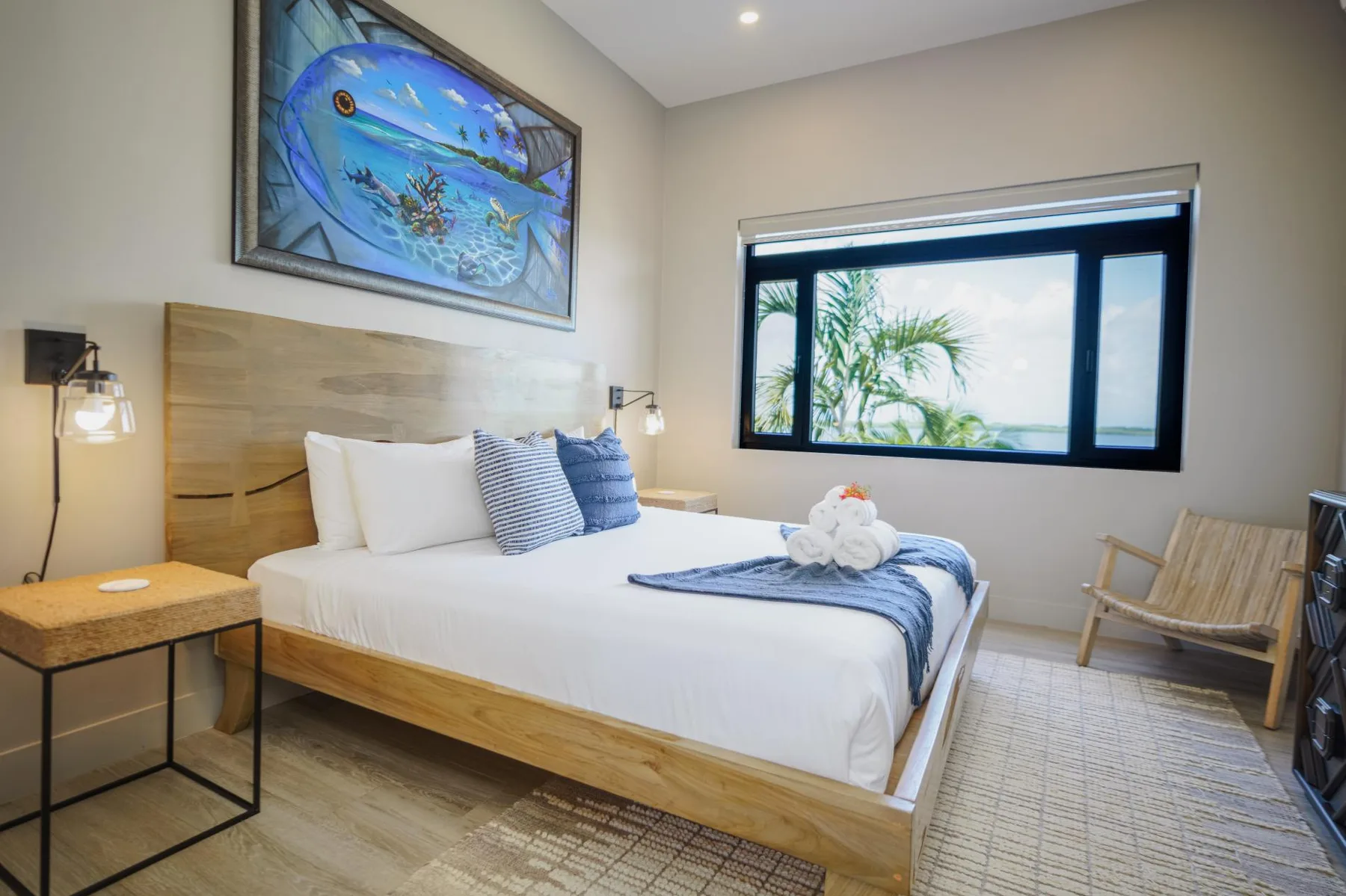 A bright bedroom with a wooden bed, blue accents, and a large window.