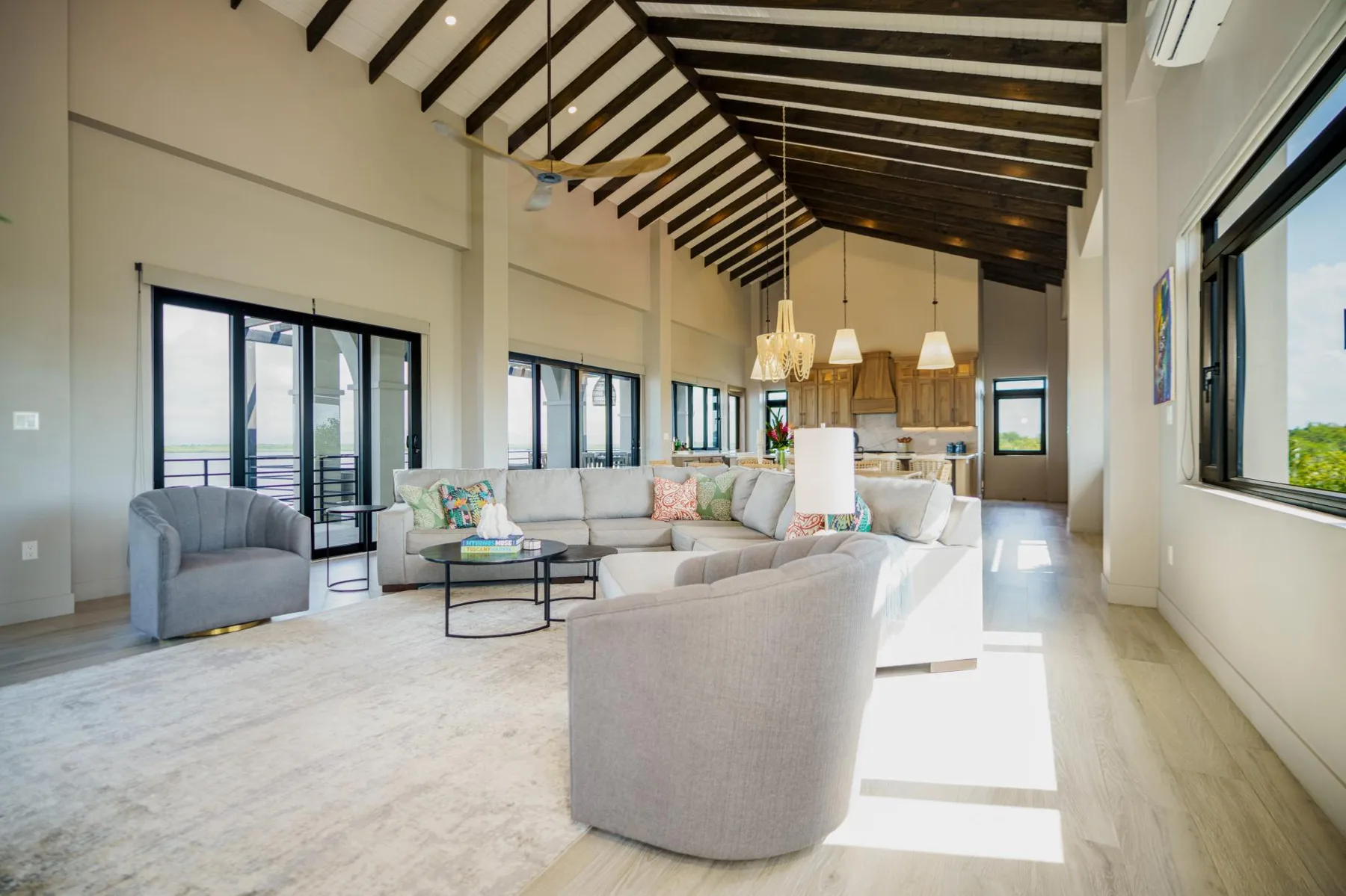 A bright living room with seating beneath a high exposed-beam ceiling.