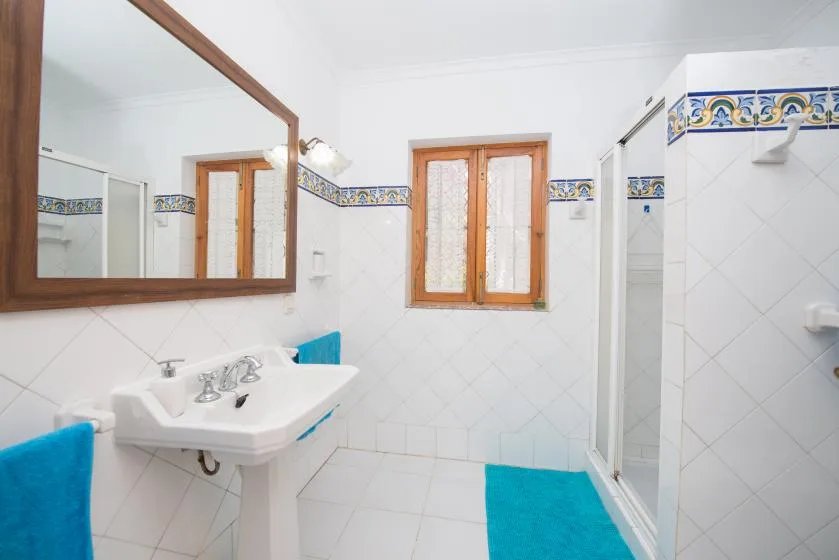 A bright bathroom with a sink, wall mirror, and turquoise towels.