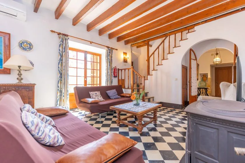 A living room with seating around a low table beneath exposed wooden ceiling beams.